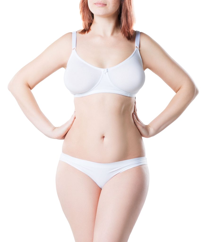 Front view of a woman standing with her hands on hips, showcasing flat abdomen.