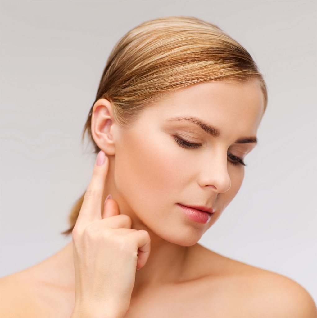 A woman pointing to her ear posing as an ear surgery model.