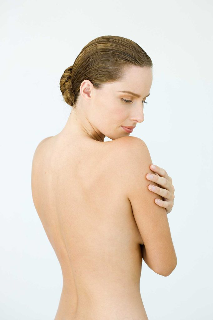 A woman with her back facing the camera with no visible moles.