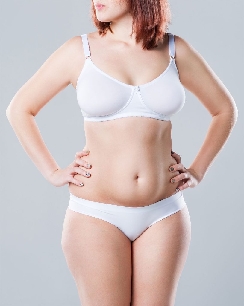 A woman in underwear with hands on her hips showing her flat stomach.